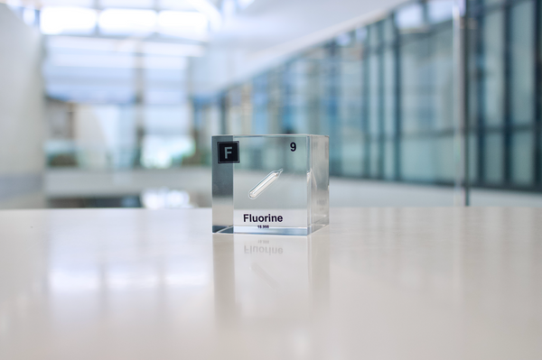 Clear acrylic cube encasing a Fluorine ampule with its atomic number 9. Ideal for display in educational settings, scientific collections, or as a decorative piece.