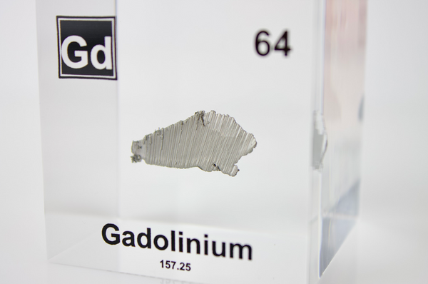 Clear acrylic cube displaying a Gadolinium element (Atomic Number 64) embedded within, offering a scientific presentation for collectors and science enthusiasts.