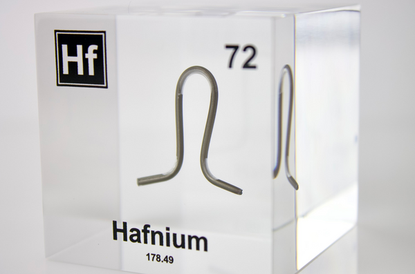 Clear acrylic cube displaying a Hafnium element (Atomic Number 72) embedded within, offering a scientific presentation for collectors and science enthusiasts.