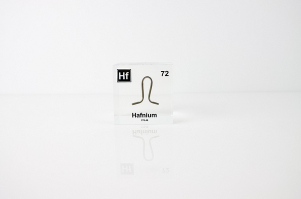 Clear acrylic cube displaying a Hafnium element (Atomic Number 72) embedded within, offering a scientific presentation for collectors and science enthusiasts.