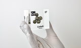 A hand holds cobalt element, Atomic Number 27, in a clear acrylic cube, displaying its name, atomic number, and key properties as shown on the periodic table. An educational and informative piece ideal for science enthusiasts and collectors.