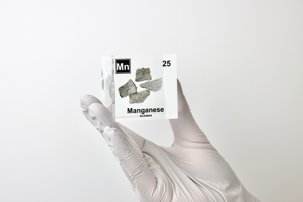 Manganese element held up in a clear acrylic cube, showcasing its name, atomic number, and properties as displayed on the periodic table. A stylish and informative piece for collectors and educators.