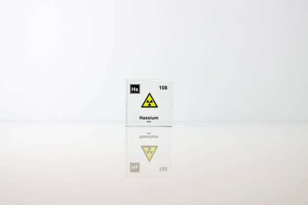 Clear acrylic cube displaying a Hassium element (Atomic Number 108) embedded within, offering a scientific presentation for collectors and science enthusiasts.