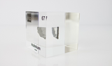 Clear acrylic cube displaying a Holmium element (Atomic Number 67) embedded within, offering a scientific presentation for collectors and science enthusiasts.