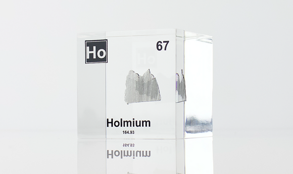 Clear acrylic cube displaying a Holmium element (Atomic Number 67) embedded within, offering a scientific presentation for collectors and science enthusiasts.