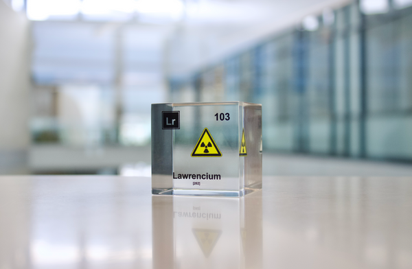 Clear acrylic cube displaying a Lawrencium element (Atomic Number 103) embedded within, offering a scientific presentation for collectors and science enthusiasts.