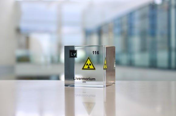 Clear acrylic cube displaying a Livermorium element (Atomic Number 116) embedded within, offering a scientific presentation for collectors and science enthusiasts.