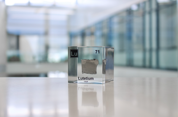 Clear acrylic cube displaying a Lutetium element (Atomic Number 71) embedded within, offering a scientific presentation for collectors and science enthusiasts.