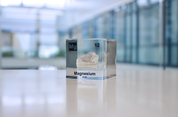 Clear acrylic cube featuring a Magnesium ampule with its atomic number 12. Ideal for educational displays, scientific collections, or as a distinctive decorative item.