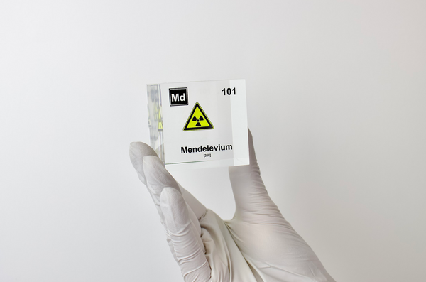 Clear acrylic cube displaying a Mendelevium element (Atomic Number 101) embedded within, offering a scientific presentation for collectors and science enthusiasts.