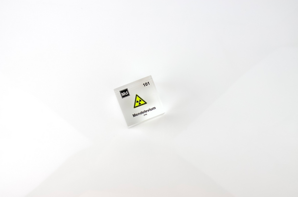 Clear acrylic cube displaying a Mendelevium element (Atomic Number 101) embedded within, offering a scientific presentation for collectors and science enthusiasts.