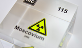 Clear acrylic cube displaying a Moscovium element (Atomic Number 115) embedded within, offering a scientific presentation for collectors and science enthusiasts.