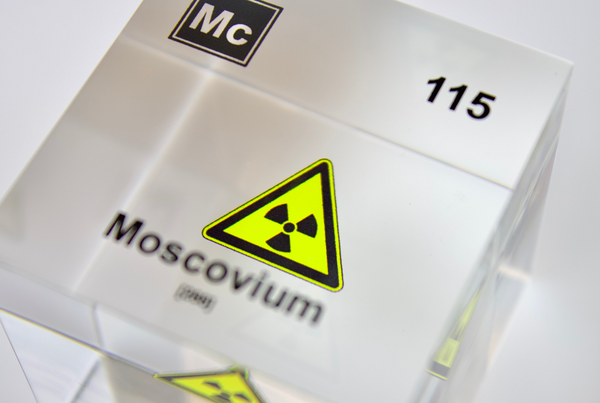 Clear acrylic cube displaying a Moscovium element (Atomic Number 115) embedded within, offering a scientific presentation for collectors and science enthusiasts.