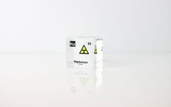 Clear acrylic cube displaying a Neptunium element (Atomic Number 93) embedded within, offering a scientific presentation for collectors and science enthusiasts.