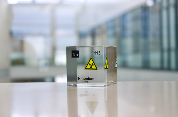 Clear acrylic cube displaying a Nihonium element (Atomic Number 113) embedded within, offering a scientific presentation for collectors and science enthusiasts.