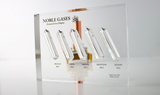 Close-up of a noble gas display made of acrylic. The display features several sections, each containing a different noble gas in its inert, gaseous form, with clear labels identifying each gas. 