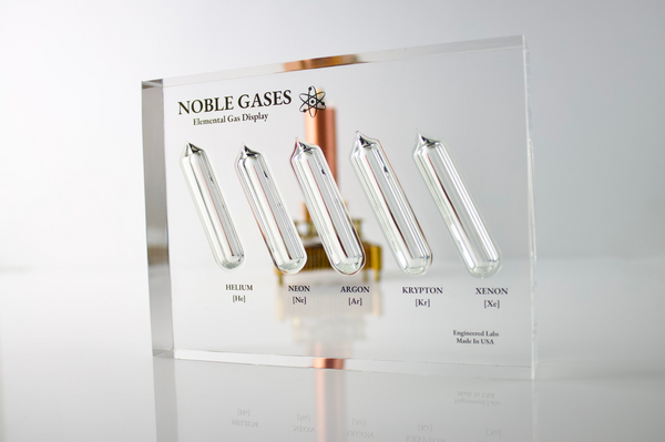 Close-up of a noble gas display made of acrylic. The display features several sections, each containing a different noble gas in its inert, gaseous form, with clear labels identifying each gas. 