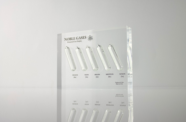 Close-up of a noble gas display made of acrylic. The display features several sections, each containing a different noble gas in its inert, gaseous form, with clear labels identifying each gas. 