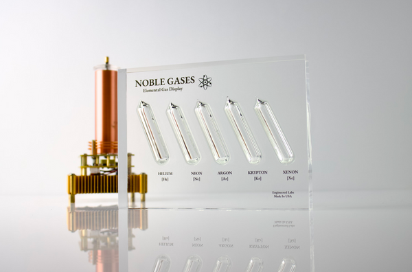 Close-up of a noble gas display made of acrylic. The display features several sections, each containing a different noble gas in its inert, gaseous form, with clear labels identifying each gas. 