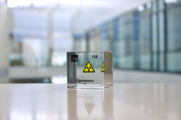 Clear acrylic cube displaying an Oganesson element (Atomic Number 118) embedded within, offering a scientific presentation for collectors and science enthusiasts.