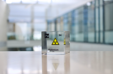 Clear acrylic cube displaying a Plutonium element (Atomic Number 94) embedded within, offering a scientific presentation for collectors and science enthusiasts.