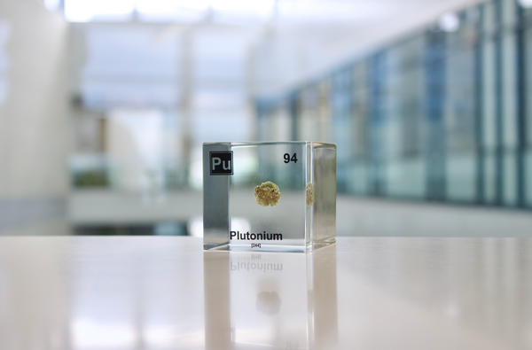 Clear acrylic cube displaying a Plutonium element (Atomic Number 94) embedded within, offering a scientific presentation for collectors and science enthusiasts.