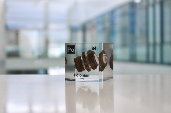 Clear acrylic cube displaying a Polonium element (Atomic Number 84) embedded within, offering a scientific presentation for collectors and science enthusiasts.