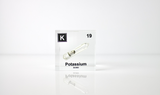 Clear acrylic cube displaying a Potassium element (Atomic Number 19) embedded within, offering a scientific presentation for collectors and science enthusiasts.