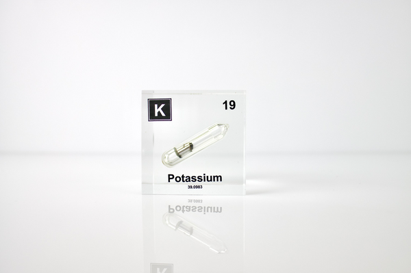 Clear acrylic cube displaying a Potassium element (Atomic Number 19) embedded within, offering a scientific presentation for collectors and science enthusiasts.