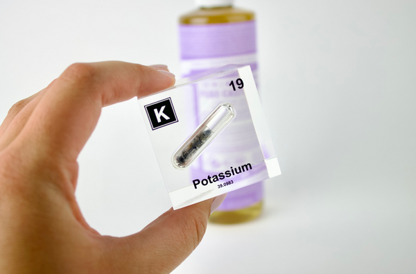 Clear acrylic cube displaying a Potassium element (Atomic Number 19) embedded within, offering a scientific presentation for collectors and science enthusiasts.