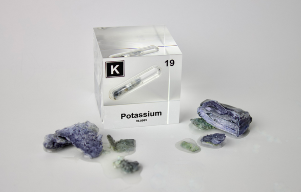 Clear acrylic cube displaying a Potassium element (Atomic Number 19) embedded within, offering a scientific presentation for collectors and science enthusiasts.