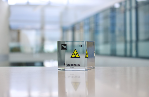 Clear acrylic cube displaying a Protactinium element (Atomic Number 91) embedded within, offering a scientific presentation for collectors and science enthusiasts.