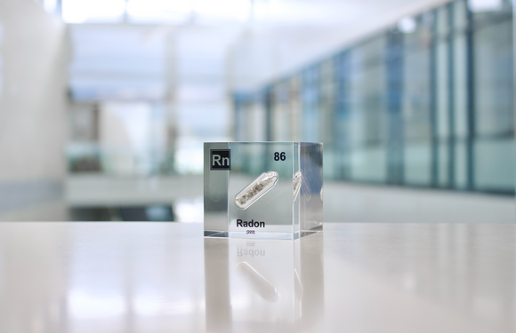 Clear acrylic cube displaying a Radon element (Atomic Number 86) embedded within, offering a scientific presentation for collectors and science enthusiasts.