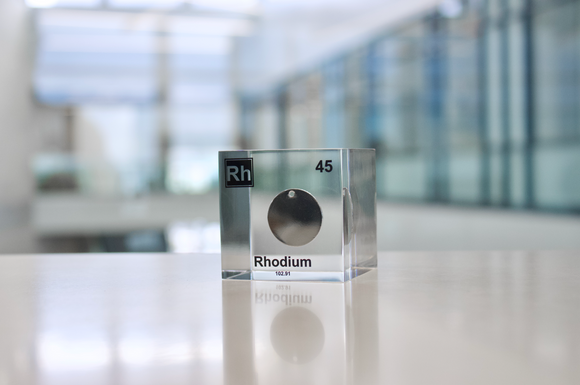 Clear acrylic cube displaying a Rhodium element (Atomic Number 45) embedded within, offering a scientific presentation for collectors and science enthusiasts.