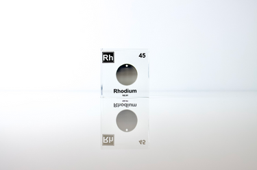 Clear acrylic cube displaying a Rhodium element (Atomic Number 45) embedded within, offering a scientific presentation for collectors and science enthusiasts.