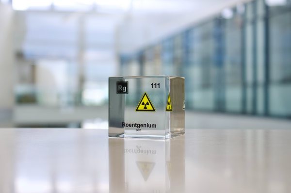 Clear acrylic cube displaying a Roentgenium element (Atomic Number 111) embedded within, offering a scientific presentation for collectors and science enthusiasts.