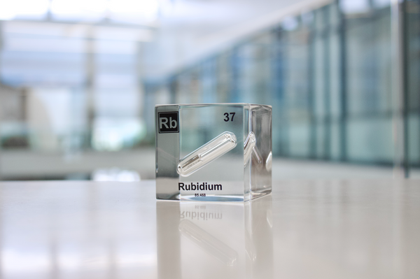 Clear acrylic cube displaying a Rubidium element (Atomic Number 37) embedded within, offering a scientific presentation for collectors and science enthusiasts.