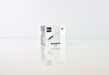 Clear acrylic cube displaying a Rubidium element (Atomic Number 37) embedded within, offering a scientific presentation for collectors and science enthusiasts.