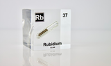 Clear acrylic cube displaying a Rubidium element (Atomic Number 37) embedded within, offering a scientific presentation for collectors and science enthusiasts.