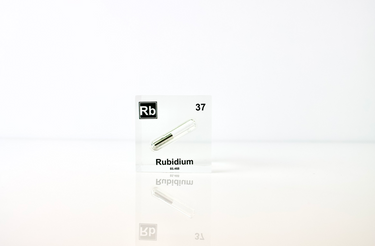 Clear acrylic cube displaying a Rubidium element (Atomic Number 37) embedded within, offering a scientific presentation for collectors and science enthusiasts.