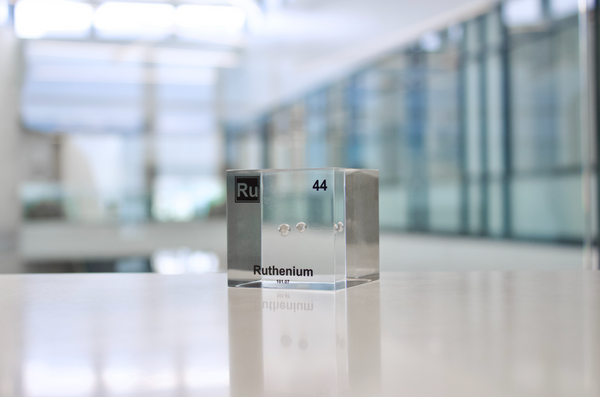 Clear acrylic cube displaying a Ruthenium element (Atomic Number 44) embedded within, offering a scientific presentation for collectors and science enthusiasts.