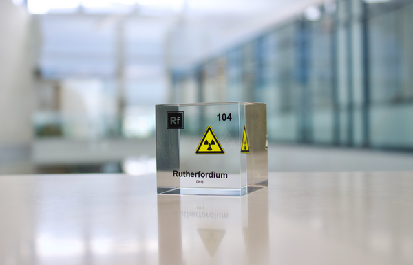 Clear acrylic cube displaying a Rutherfordium element (Atomic Number 104) embedded within, offering a scientific presentation for collectors and science enthusiasts.