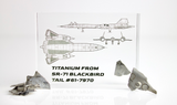 Close-up piece of SR-71 Blackbird titanium embedded in clear acrylic. The fragment is metallic and jagged, which highlights its history from the high-speed reconnaissance aircraft. A blueprint of the SR-71 aircraft is visible in the display.