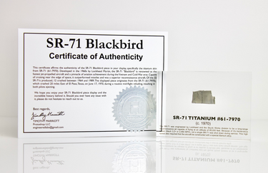 Close-up piece of SR-71 Blackbird titanium embedded in clear acrylic. The fragment is metallic and jagged, which highlights its history from the high-speed reconnaissance aircraft.