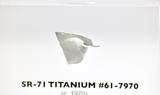 Close-up piece of SR-71 Blackbird titanium embedded in clear acrylic. The fragment is metallic and jagged, which highlights its history from the high-speed reconnaissance aircraft.