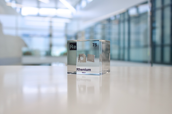 Rhenium element in a clear acrylic cube, featuring its name, atomic number, and properties as shown on the periodic table. A sleek and educational display for collectors and enthusiasts.