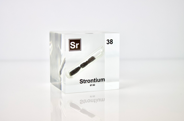 Clear acrylic cube displaying a Strontium element (Atomic Number 38) embedded within, offering a scientific presentation for collectors and science enthusiasts.