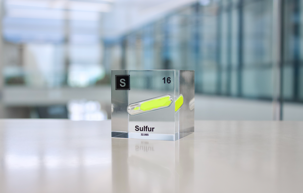 Clear acrylic cube displaying a Sulfur element (Atomic Number 16) embedded within, offering a scientific presentation for collectors and science enthusiasts.