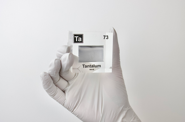 Clear acrylic cube displaying a Tantalum element (Atomic Number 73) embedded within, offering a scientific presentation for collectors and science enthusiasts.