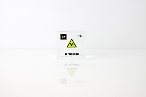 Clear acrylic cube displaying a Tennessine element (Atomic Number 117) embedded within, offering a scientific presentation for collectors and science enthusiasts.